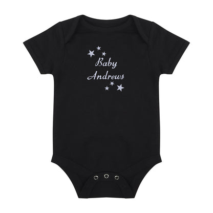 A black short-sleeve baby bodysuit with 'Baby Andrews' and small stars embroidered in white on the chest, displayed flat against a white background.