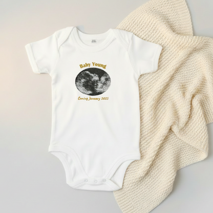 White baby onesie with scan photo embroidered and text on a light background