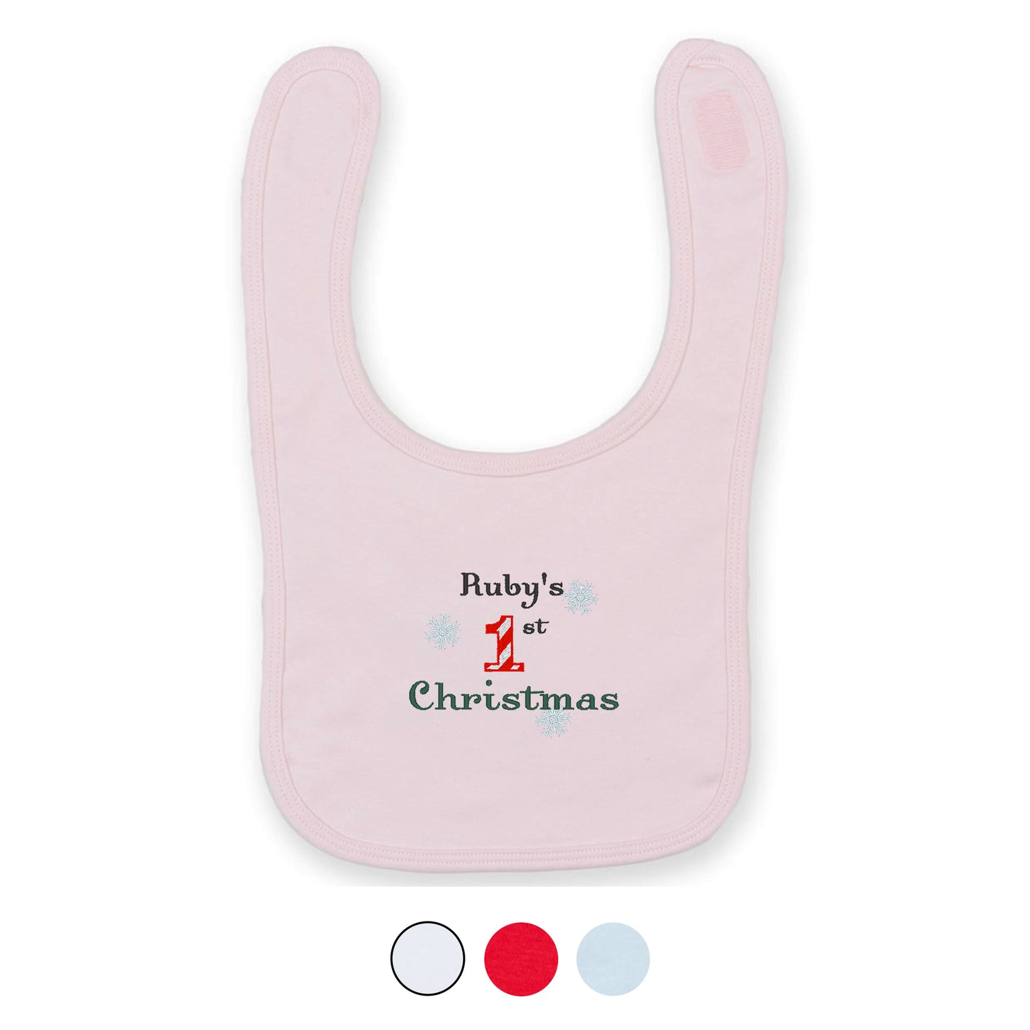 A pink baby bib with embroidered text 'Ruby's 1st Christmas' and a snowflake design
