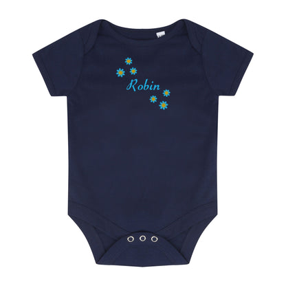 A navy blue short-sleeve baby bodysuit with three silver snap closures at the crotch. The chest features a personalized design with the name 'Robin' in light blue cursive script, surrounded by small yellow and blue daisy flowers.