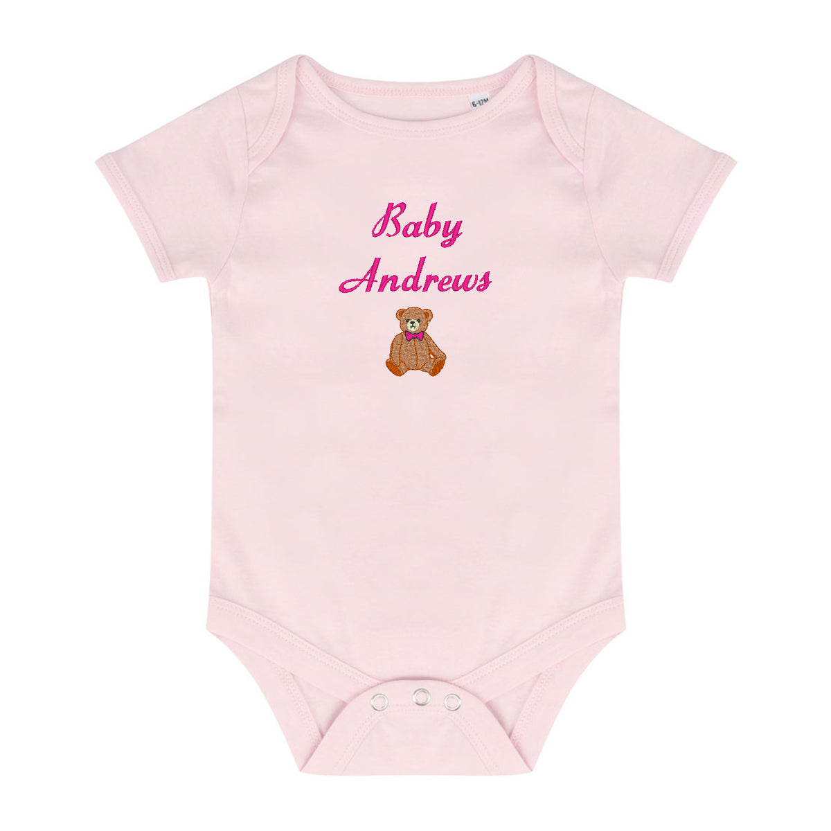 A light pink short-sleeve baby bodysuit with 'Baby Andrews' embroidered in pink script on the chest, above a small brown teddy bear wearing a pink bow tie. The bodysuit has three snap closures at the crotch and is shown flat against a white background.