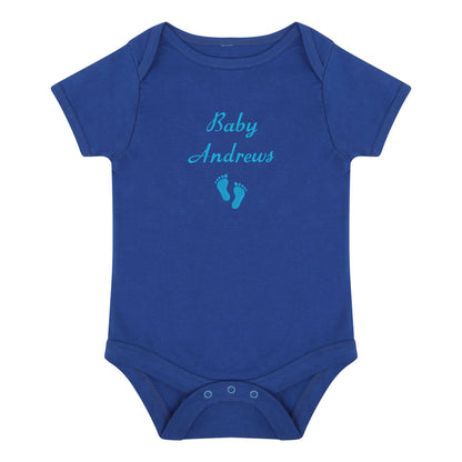 A royal blue short-sleeve baby bodysuit with 'Baby Andrews' and a pair of baby feet embroidered in light blue on the chest, displayed on a solid white background.