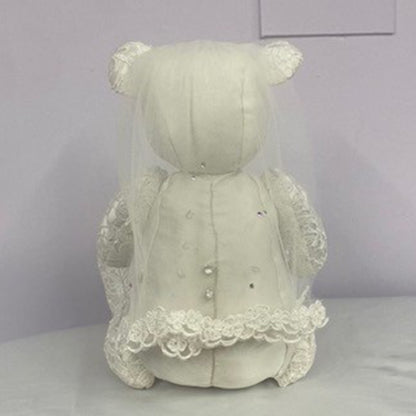 White teddy bear with a lace dress on a plain background