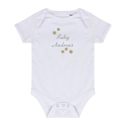 A white short-sleeve baby bodysuit with 'Baby Andrews' embroidered in gray script on the chest, decorated with small yellow and white daisy flowers, shown on a plain white background.