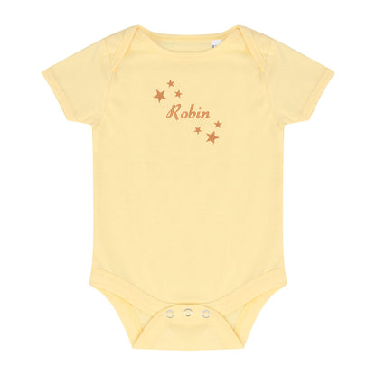A pale yellow short-sleeve baby bodysuit with 'Robin' and small stars embroidered in brown on the chest, displayed flat against a white background.